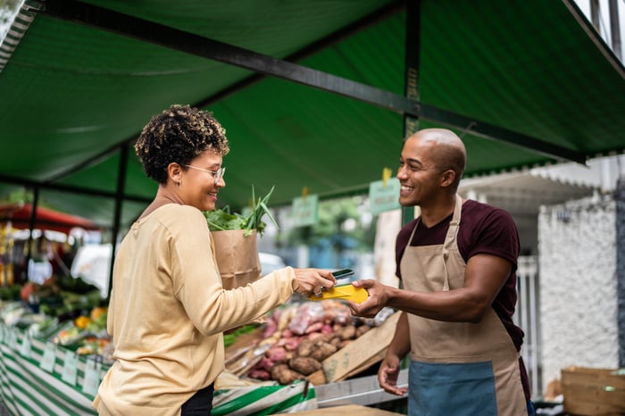 Person making a digital payment at an outdoor vendor.