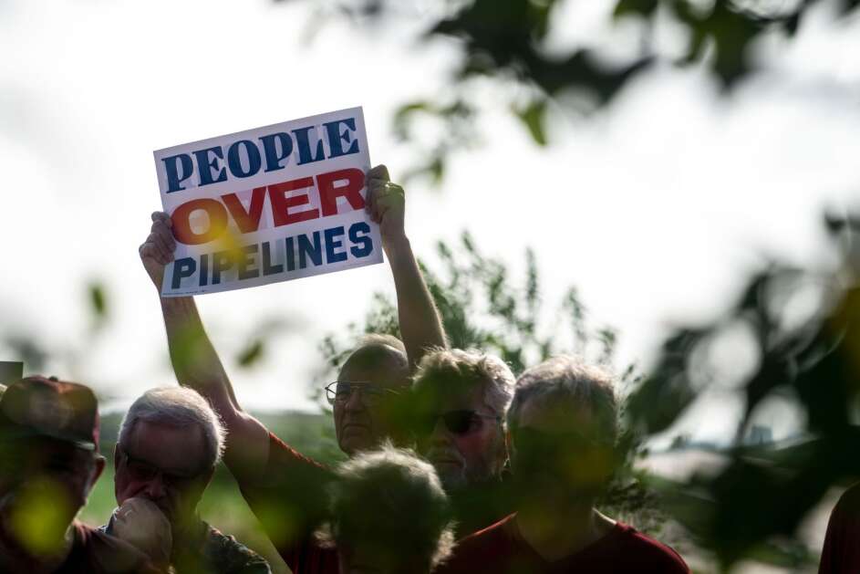 Landowners hold signs during a press conference by opponents of the Summit Carbon Solutions pipeline on Tuesday, Aug. 22, 2023, in Fort Dodge, Iowa. Public utility regulators in Iowa will begin a hearing Tuesday on a proposed carbon dioxide pipeline for transporting emissions of the climate-warming greenhouse gas for storage underground that has been met by resistant landowners who fear the taking of their land and dangers of a pipeline rupture. (Lily Smith/The Des Moines Register via AP)