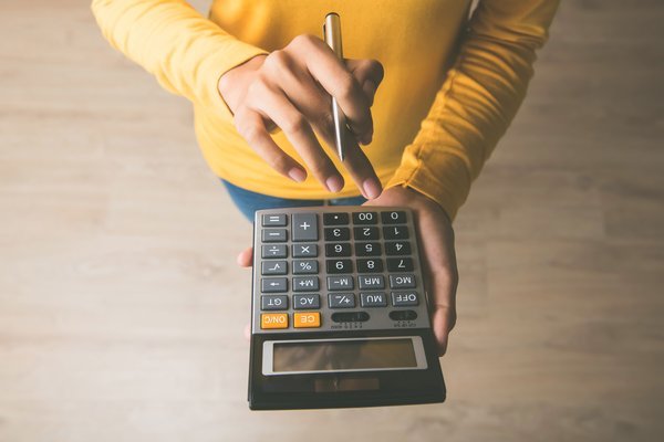 A person using a calculator and holding a pen.